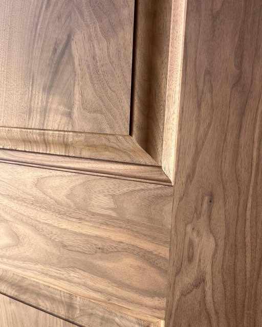 Close-up of a wood door panel showing its shaped border and flowing grain